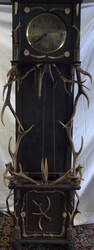 Grandfather clock, elaborately decorated with antlers, dark wood. ...